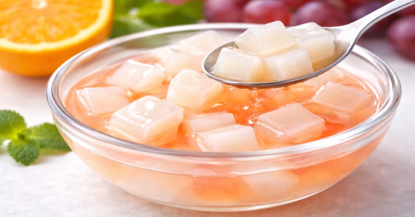 Close-up of homemade jelly fruits in syrup showing soft gelatin texture and glossy surface
