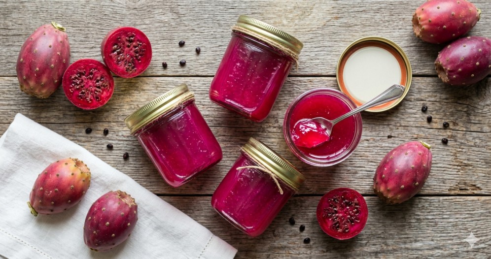 Homemade cactus fruit jelly in glass jars with fresh prickly pear fruit on wooden surface