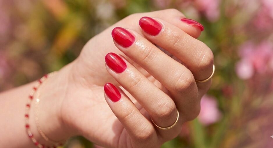 Glossy cherry red jelly nail polish manicure on short oval nails